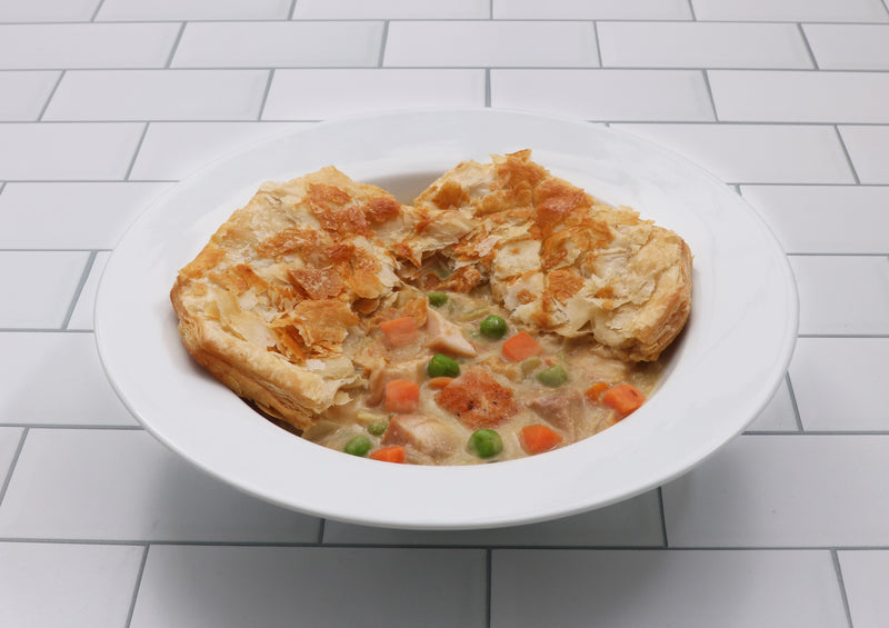 Chicken Pot pie with vegetables in a white bowl on a tiled floor